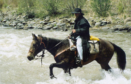 Daniel Pope rides a horse through a river